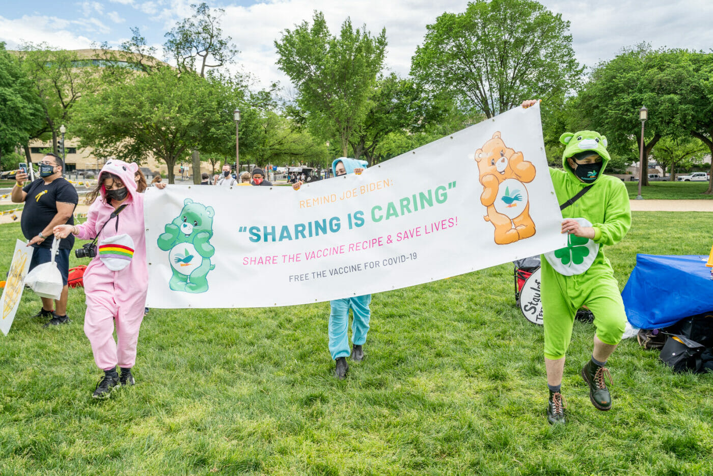 Care Bears hold a banner aloft reading "Sharing is Caring"