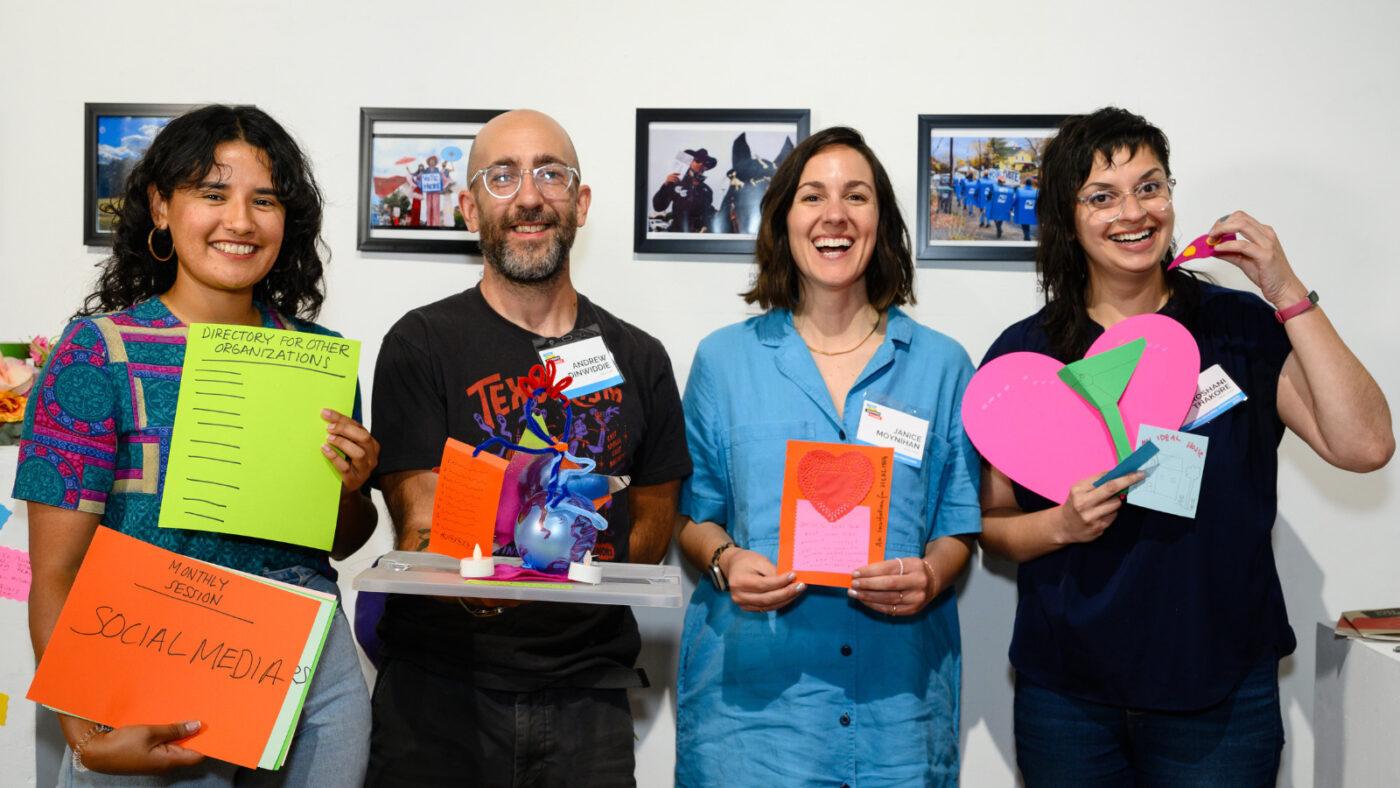 Four people smiling and holding up their workshop prototypes