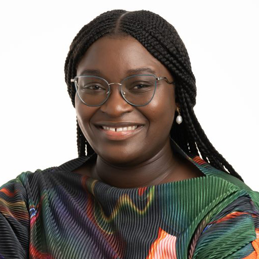Temitope Amoye smiling at front of camera, wearing glasses and a colorful shirt. 