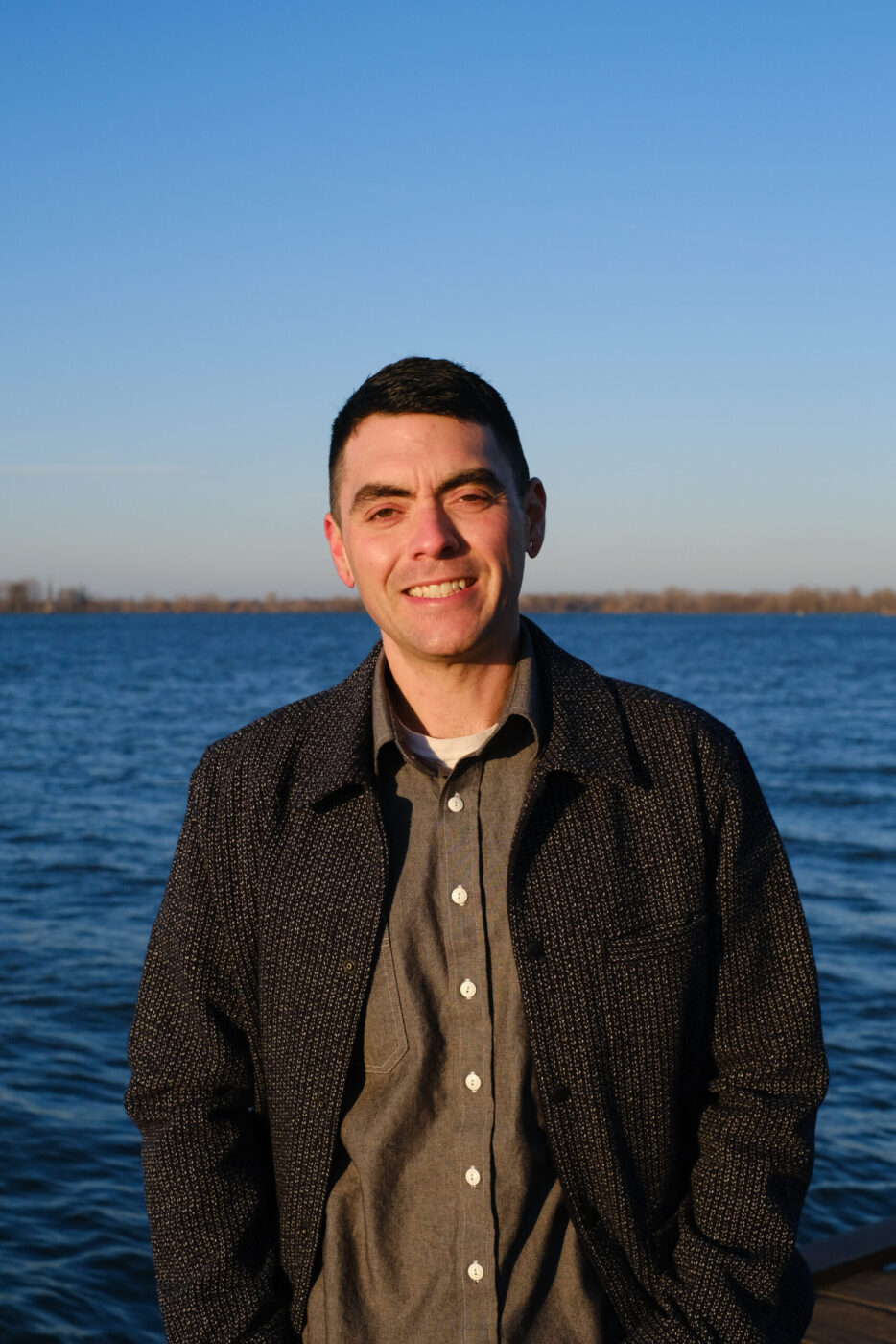 Patrick Fisher standing in front of a blue body of water and blue sky